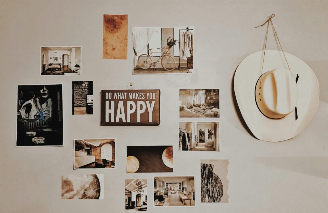 Neutral home wall featuring an inspirational "Do What Makes You Happy" sign, a hanging white hat, and an eclectic arrangement of framed prints and photos, creating a cozy and calming gallery-style décor.