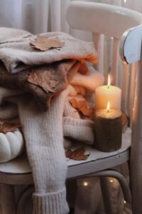 Cozy blanket draped over a chair with a lit candle, creating a warm and inviting atmosphere for a relaxing home environment.