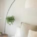 Cozy neutral bedroom setup with white and beige pillows, soft bedding, hanging plant, and small wooden side table holding a succulent, styled with calming fall-inspired accents.