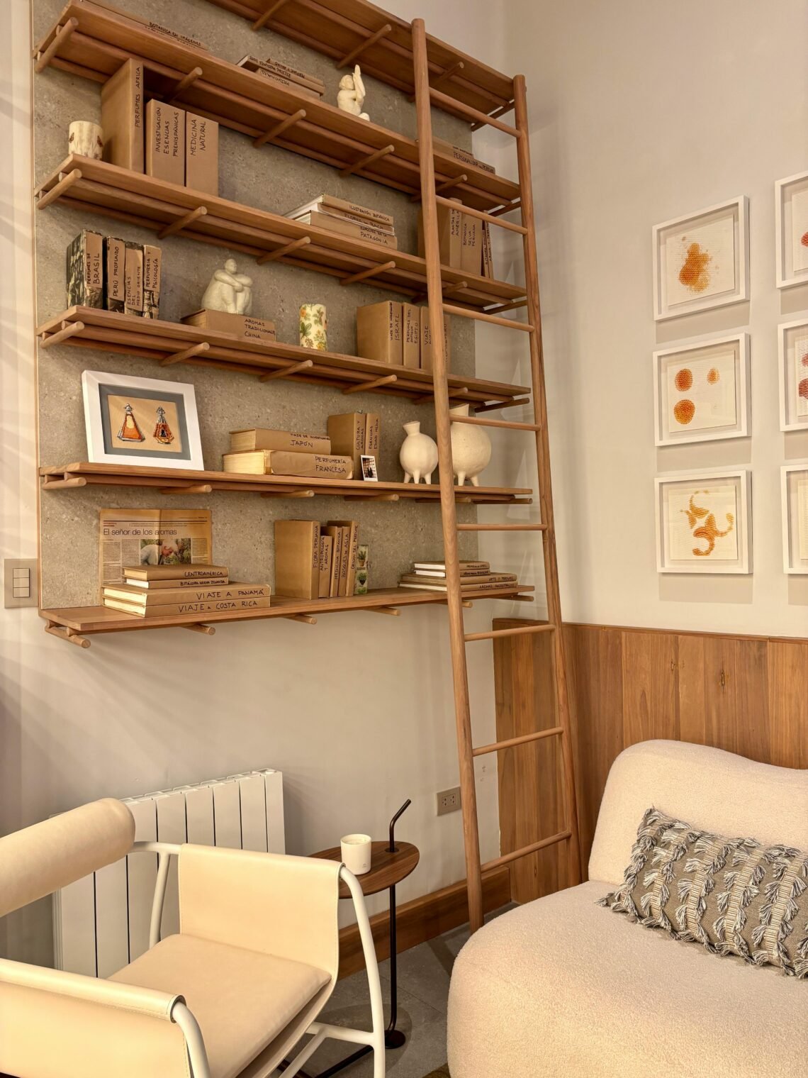 Cozy reading nook corner with wooden ladder bookshelf, neutral decor, framed art, and soft seating, styled to create a warm and inviting reading space