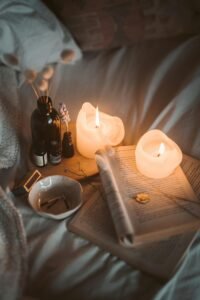 Cozy setup with lit candles, a warm drink, and a journal on a soft blanket, creating a peaceful and relaxing home environment.