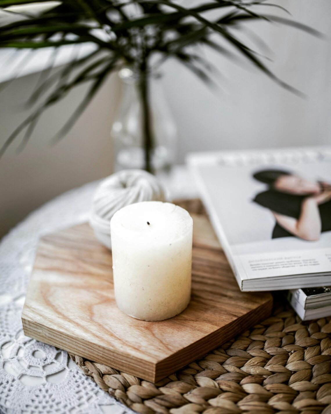 Minimal cozy flatlay showing a white candle on a wooden tray beside a lifestyle magazine and soft textures — a peaceful scene that reflects the calm, intentional style of a self-care drawer.