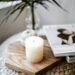 Minimal cozy flatlay showing a white candle on a wooden tray beside a lifestyle magazine and soft textures — a peaceful scene that reflects the calm, intentional style of a self-care drawer.