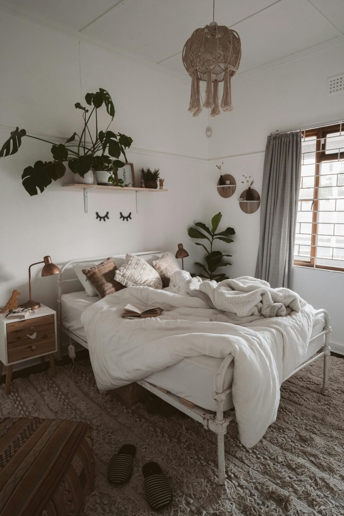 A cozy minimal bedroom with soft neutral bedding, layered blankets, and warm lighting. Natural textures, wood accents, and indoor plants create a calm, inviting retreat that perfectly captures warm minimal bedroom styling.