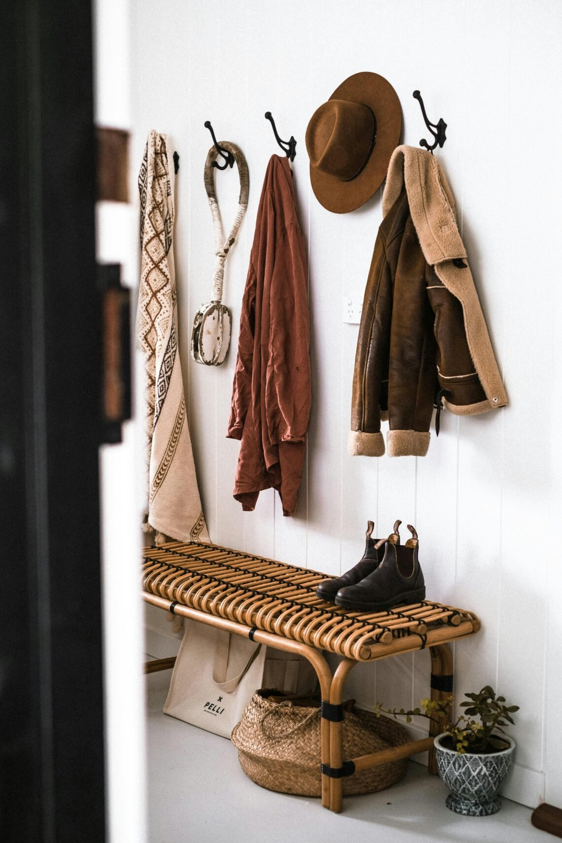 Warm neutral entryway with woven rattan bench, cozy jackets, and minimalist wall hooks styled in a calm, inviting design — an aesthetic Amazon-inspired setup that makes a small space feel welcoming.