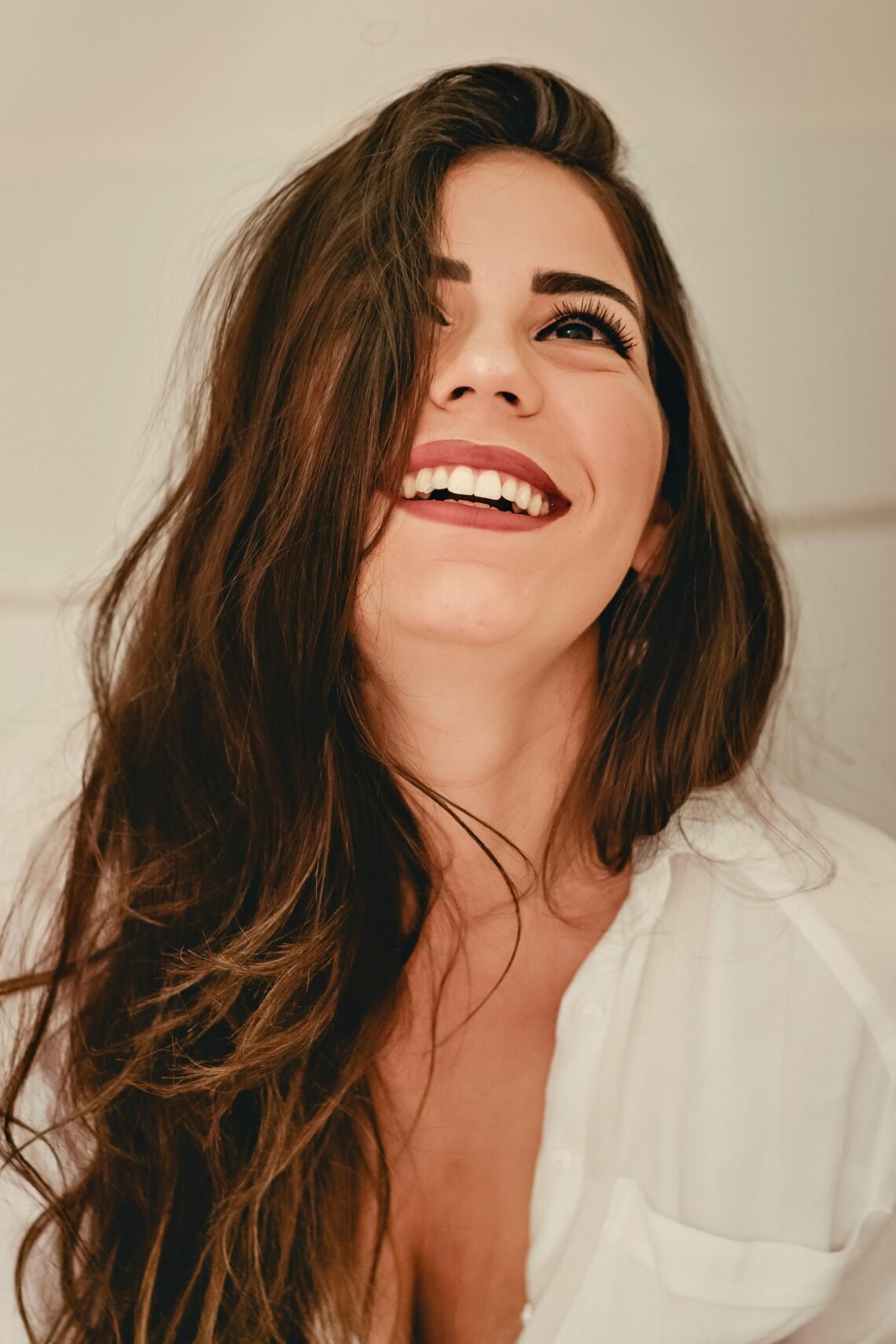 Portrait of a happy woman with long brunette hair and elegant style, expressing joy.